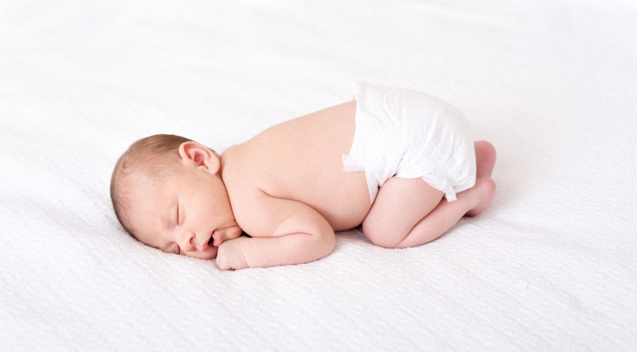 Un bambino che dorme a pochi giorni di vita, ignaro del nome che qualcun altro gli ha attribuito