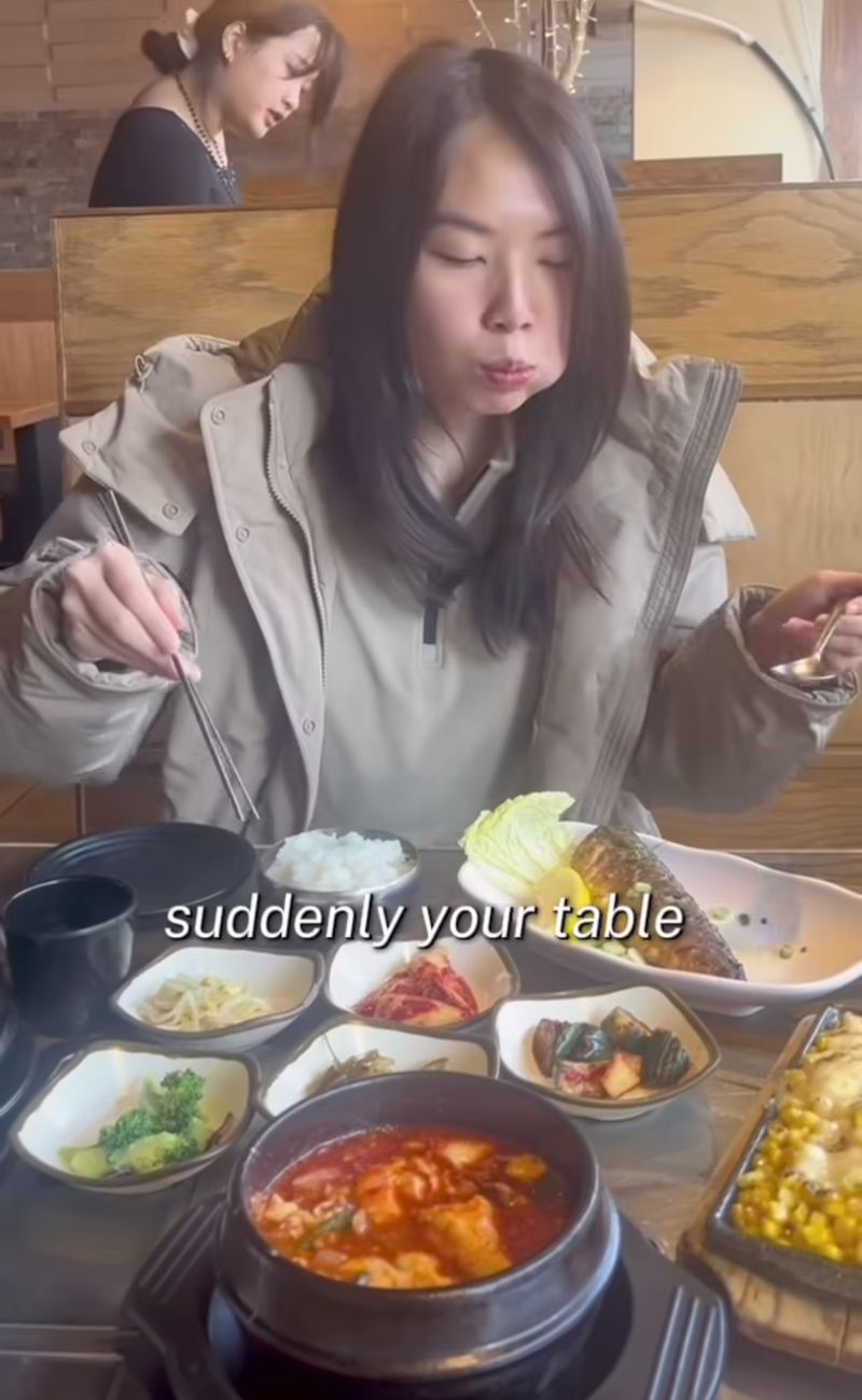 La content creator mostra i tipici piattini coreani dei contorni gratuiti serviti ai ristoranti